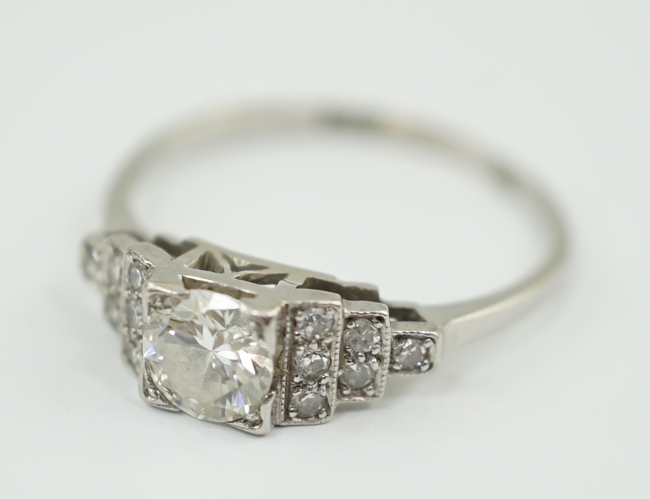 An Art Deco 18ct white gold, platinum and single stone diamond ring, with twelve stone diamond chip set stepped shoulders